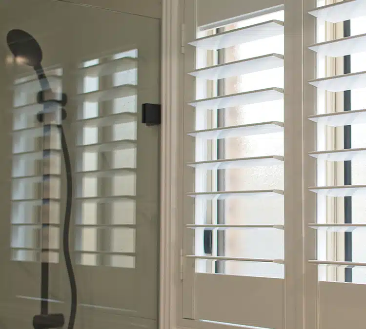 Shower with custom solid composite shutters over the window for privacy and sunlight control